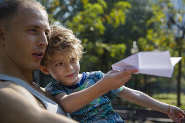 Vater mit Sohn spielt mit Papierflugzeug - IKF00209