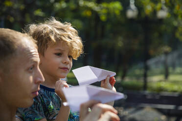Sohn und Vater spielen mit Papierfliegern - IKF00211