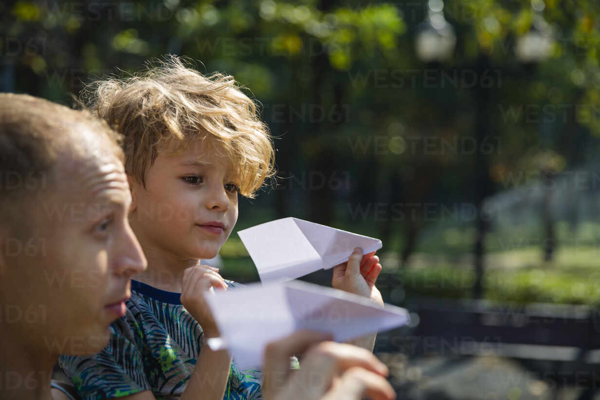 Son and father playing with paper airplanes stock photo