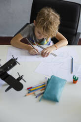 Junge zeichnet mit Bleistift auf Papier zu Hause - IKF00218