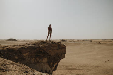 Frau steht auf einem Felsen in der Wüste - GMLF01445