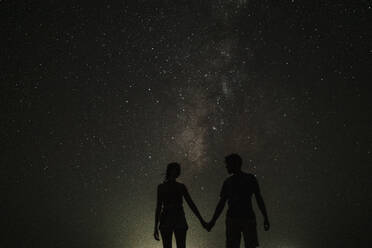 Silhouette eines sich an den Händen haltenden Paares bei Nacht - GMLF01453