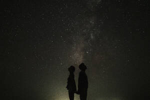 Silhouette of couple standing in front of stars at night - GMLF01454