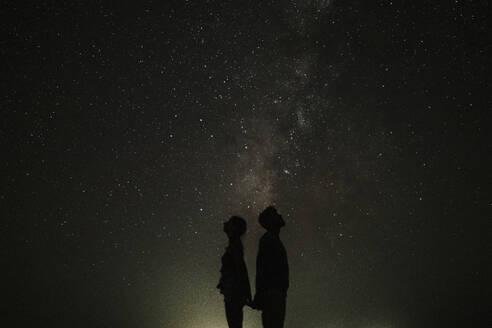 Silhouette of couple standing in front of stars at night - GMLF01454