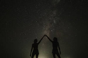 Two women touching fingers and standing in front of stars - GMLF01455