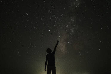 Silhouette of young man pointing towards stars - GMLF01456