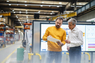 Businessman with colleague discussing in factory - DIGF19891