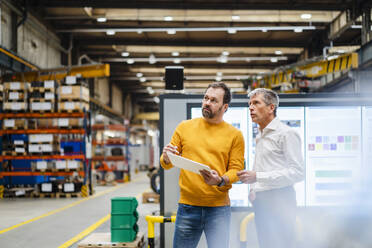 Mature businessman having discussion with colleague in factory - DIGF19893