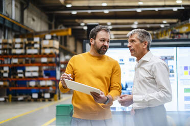 Mature businessmen having discussion together in factory - DIGF19894