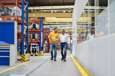 Mature businessmen having discussion and walking in factory - DIGF19903