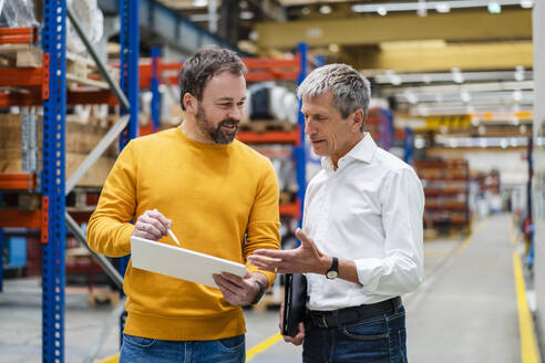 Businessman with colleague discussing in factory - DIGF19907