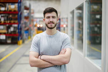 Confident employee with arms crossed at factory - DIGF19925