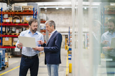 Businessman discussing with manager over laptop at factory - DIGF19930