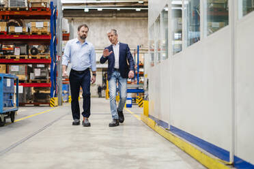 Businessman and manager walking together at factory - DIGF19933