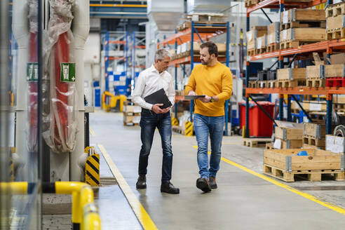 Manager und Geschäftsmann gehen zusammen in der Produktionshalle einer Fabrik - DIGF19958