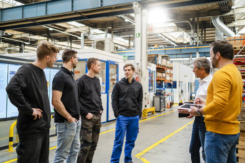 Mitarbeiter diskutieren bei einer Besprechung in der Fabrik miteinander - DIGF19975