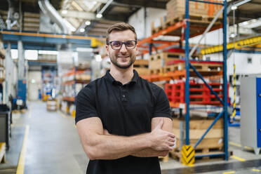 Smiling employee wearing eyeglasses at factory - DIGF19992