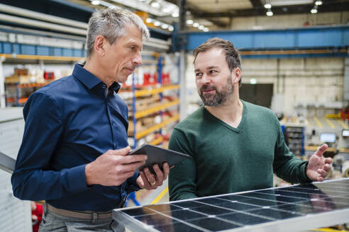 Manager explaining solar panel to businessman at factory - DIGF19994