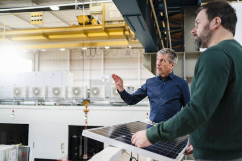 Geschäftsmann und Manager diskutieren über Solarmodule in einer Fabrik - DIGF20006