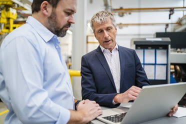 Geschäftsmann plant mit Manager über Laptop in Fabrik - DIGF20022