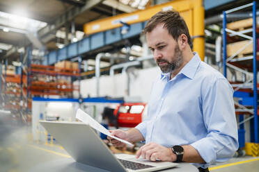 Manager prüft Dokument mit Laptop im Büro - DIGF20029