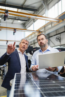 Businessman explaining manager holding laptop at factory - DIGF20033