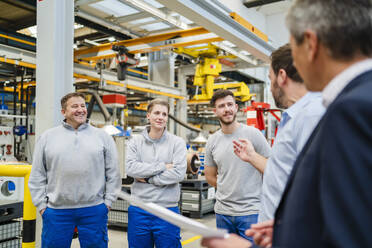 Der Manager erklärt den Mitarbeitern bei einer Besprechung in der Fabrik - DIGF20038