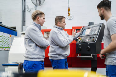 Mitarbeiter erklärt Kollegen in der Fabrik die CNC-Maschine - DIGF20042