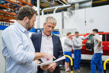 Manager erklärt einem Geschäftsmann in der Fabrik ein Dokument - DIGF20046