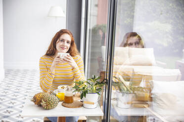 Smiling woman having healthy breakfast at table - PCLF00440