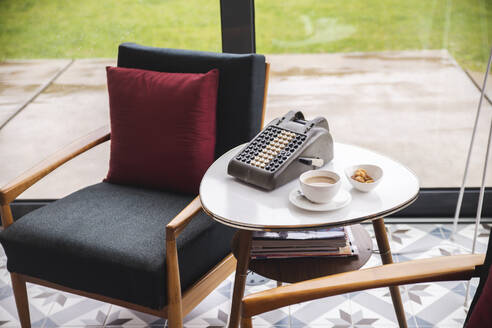 Kaffee und Kekse mit alter Rechenmaschine auf dem Tisch neben dem Stuhl - PCLF00443