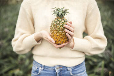 Frau hält frische Ananas in den Händen - PCLF00451