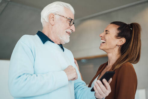 Lachende junge Frau und älterer Mann mit Smartphone - MOEF04555