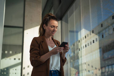 Businesswoman surfing net through smart phone at office - MOEF04597