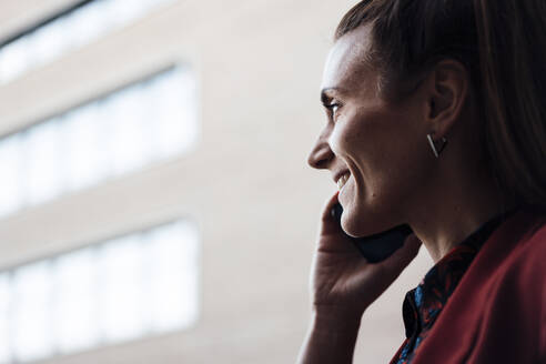 Lächelnde Geschäftsfrau, die über ein Mobiltelefon kommuniziert - MOEF04630