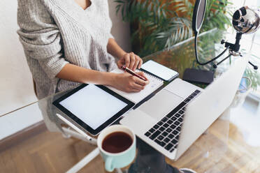 Podcaster schreibt am Schreibtisch im Home Office in sein Tagebuch - EGHF00771