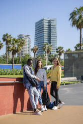 Multiracial students standing near wall in park at sunny day - IKF00225