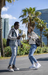 Happy students enjoying together standing in park at sunny day - IKF00233