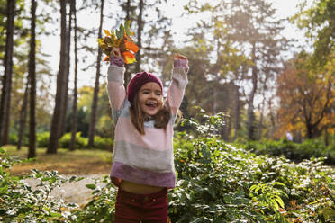 Fröhliches Mädchen spielt mit Blättern im Park - IKF00242