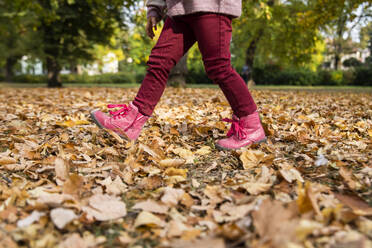 Mädchen geht auf trockenen Blättern im Herbst Park - IKF00247