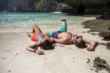 Unbeschwertes Paar am Strand im Sand liegend - IKF00263