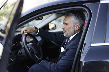 Businessman wearing suit sitting in car - JJF00775