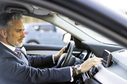 Geschäftsmann benutzt GPS im Auto sitzend - JJF00780