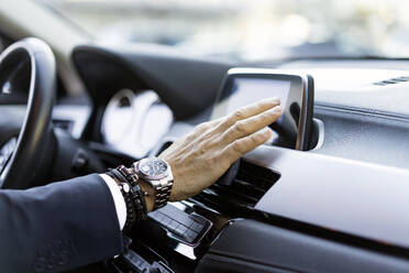 Hand eines Geschäftsmannes, der ein GPS-System im Auto benutzt - JJF00781