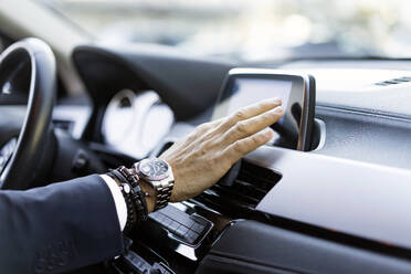 Hand of businessman using GPS system in car - JJF00781