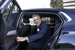 Lächelnder Geschäftsmann öffnet die Hintertür eines Autos - JJF00787