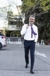 Smiling businessman walking on footpath - JJF00805