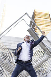 Cheerful businessman screaming in front of building - JJF00837