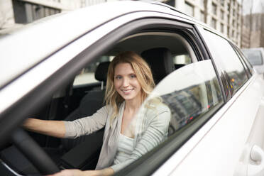 Smiling blond smiling woman driving car - PNEF02701