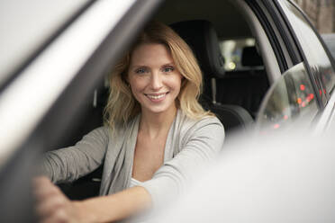 Smiling blond woman driving car - PNEF02704